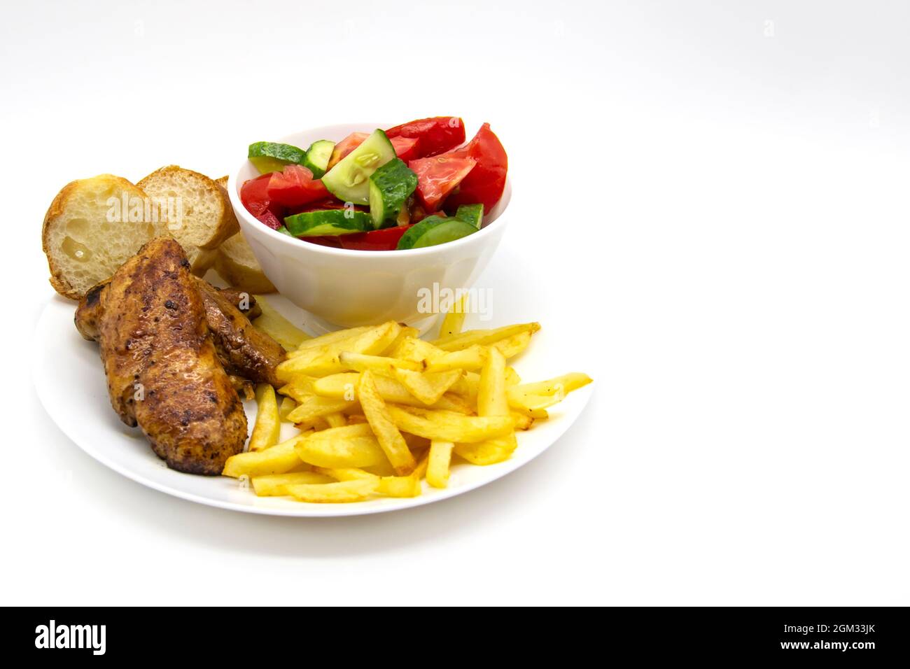 Fried chicken breast with fries, slices of bread and salad in a white plate on a light background. Fresh salad with cucumbers and tomatoes. Very tasty Stock Photo