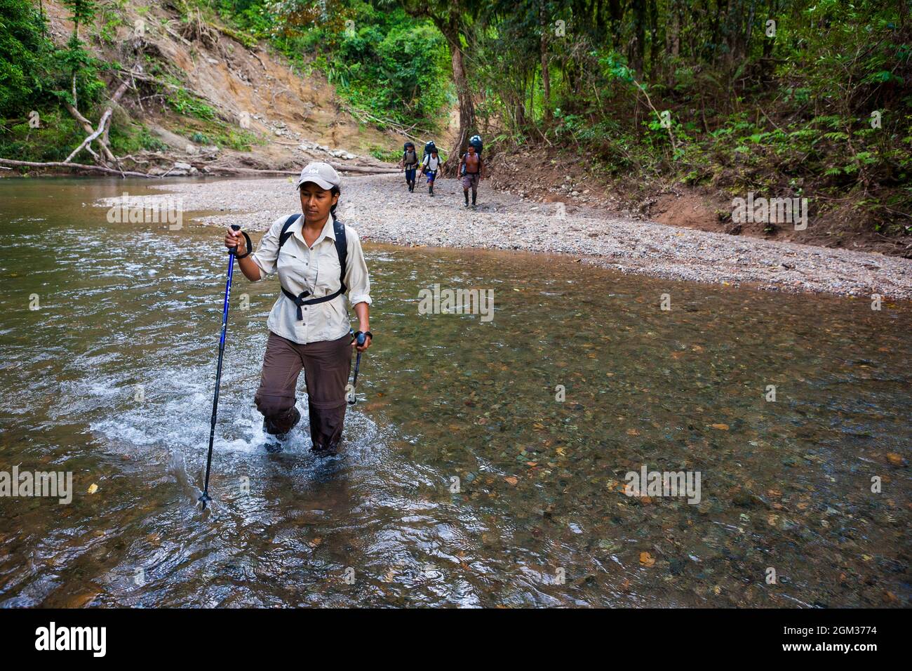 A group of panamanian hikers are crossing a river along the old Camino