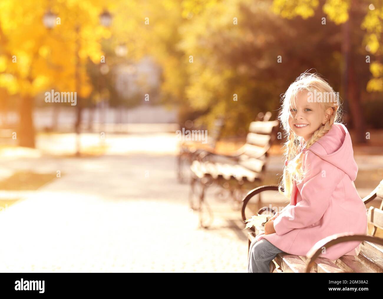Cute little girl sitting on bench in autumn park Stock Photo - Alamy