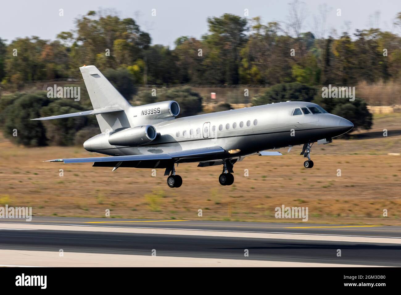 A shiny silver Dassault Falcon 900B (REG: N939SS) making a near mid-field landing. Stock Photo