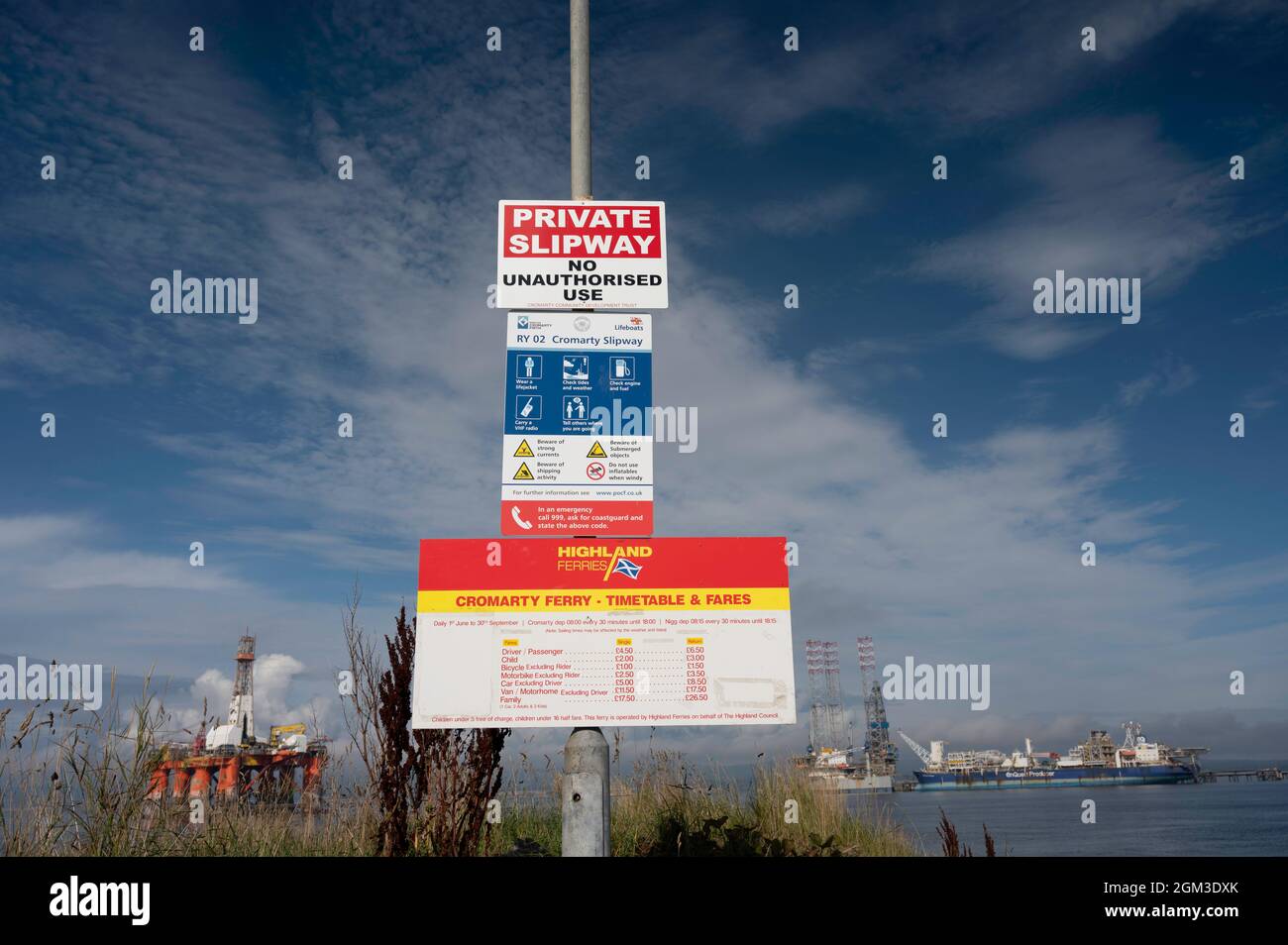 Signs for Highland Ferries, crossing from Cromarty to Nigg. Timetable, private slipway notice and prices. Sunny day with blue sky and clouds. Stock Photo