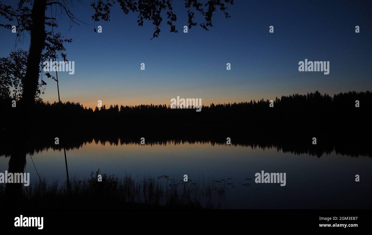 NightArt A Lake in middel Finnland with a perfect Reflection of the Nature in in It. Astonishing Suomi Stock Photo