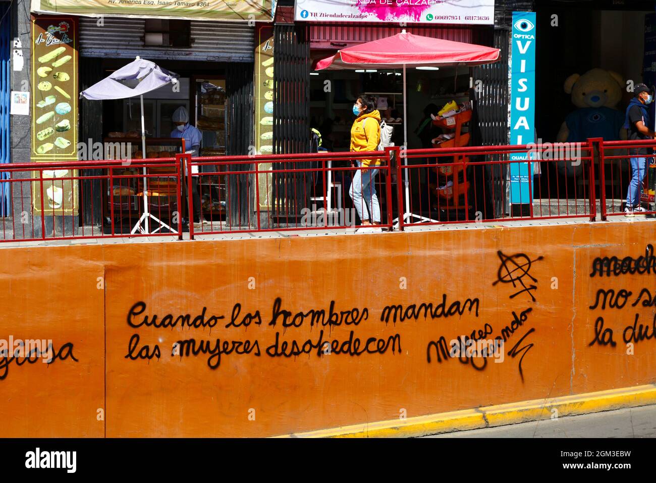 Feminist graffiti 'When Men Command Women Disobey' by the feminist group Mujeres Creando sprayed on orange painted wall, Av 6 de Agosto, La Paz, Bolivia Stock Photo