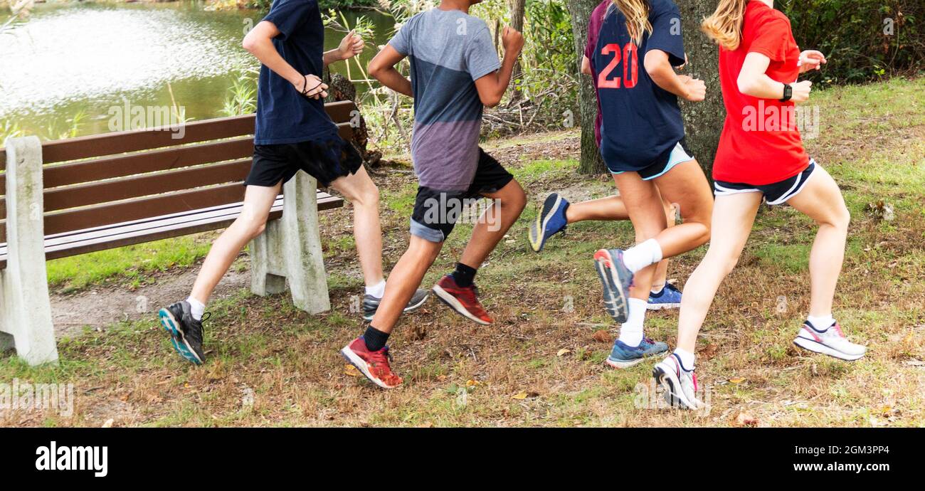 High school cross country runners running together around a lake on