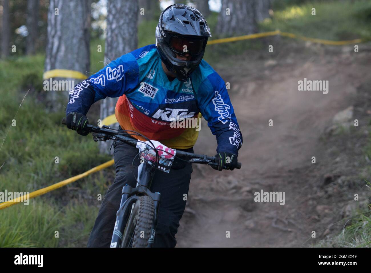 Downhill mountain biker descending during a race with dust coming from behind Stock Photo