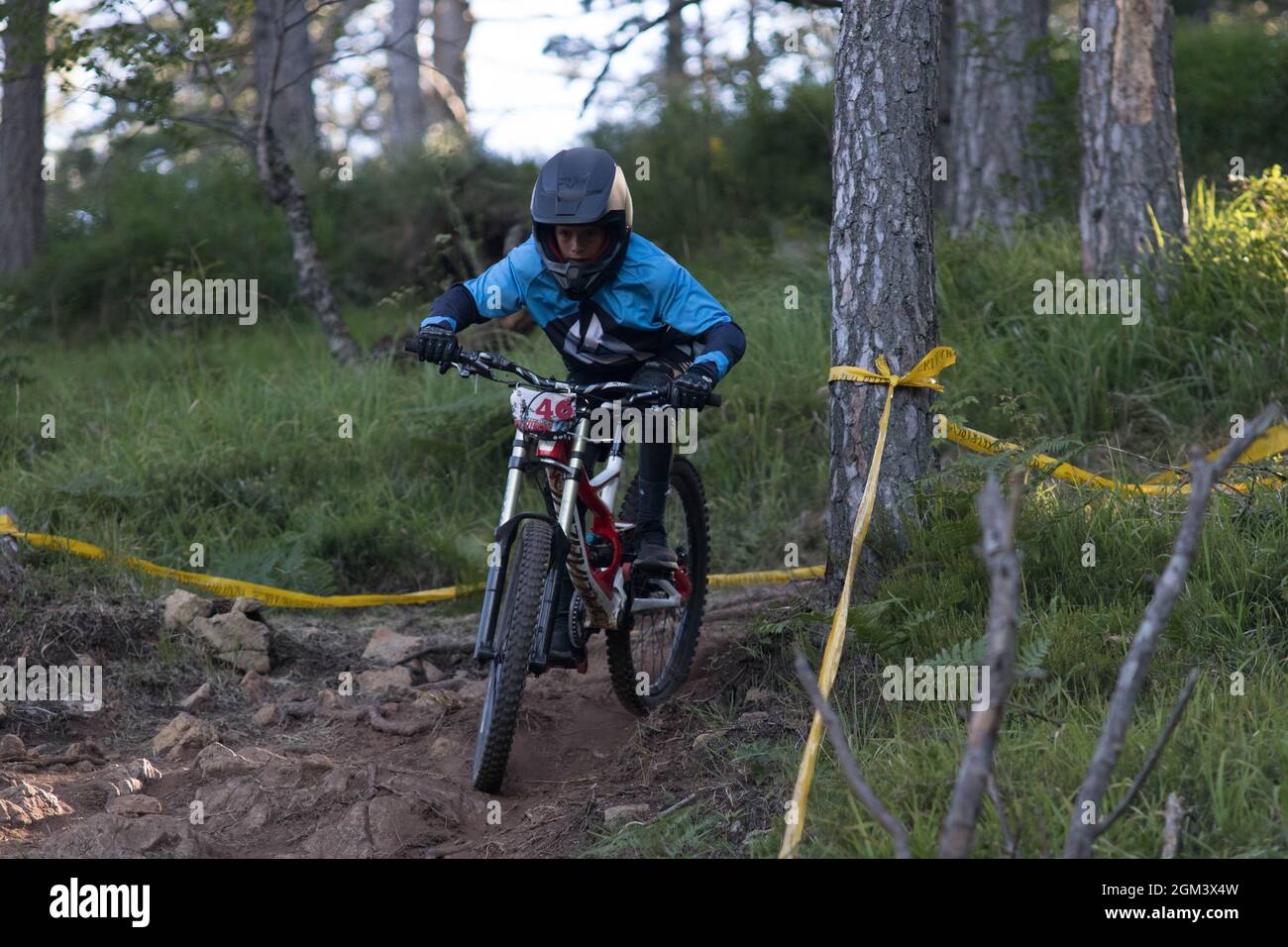 A young competitive fast downhill mountain biker driving in woods Stock Photo