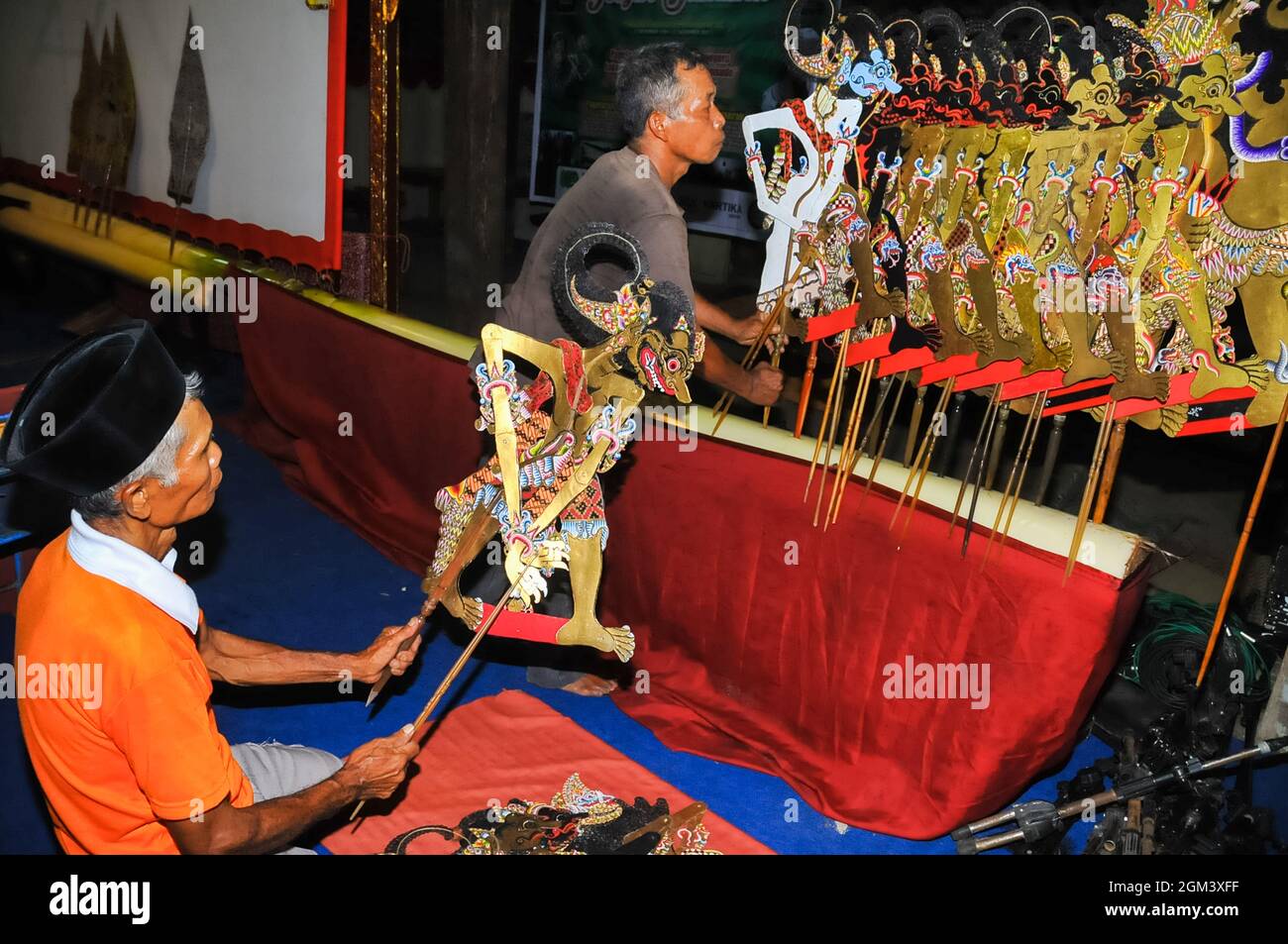 Two men are arranging puppets or wayang kulit in preparation for a shadow puppet performance. Stock Photo