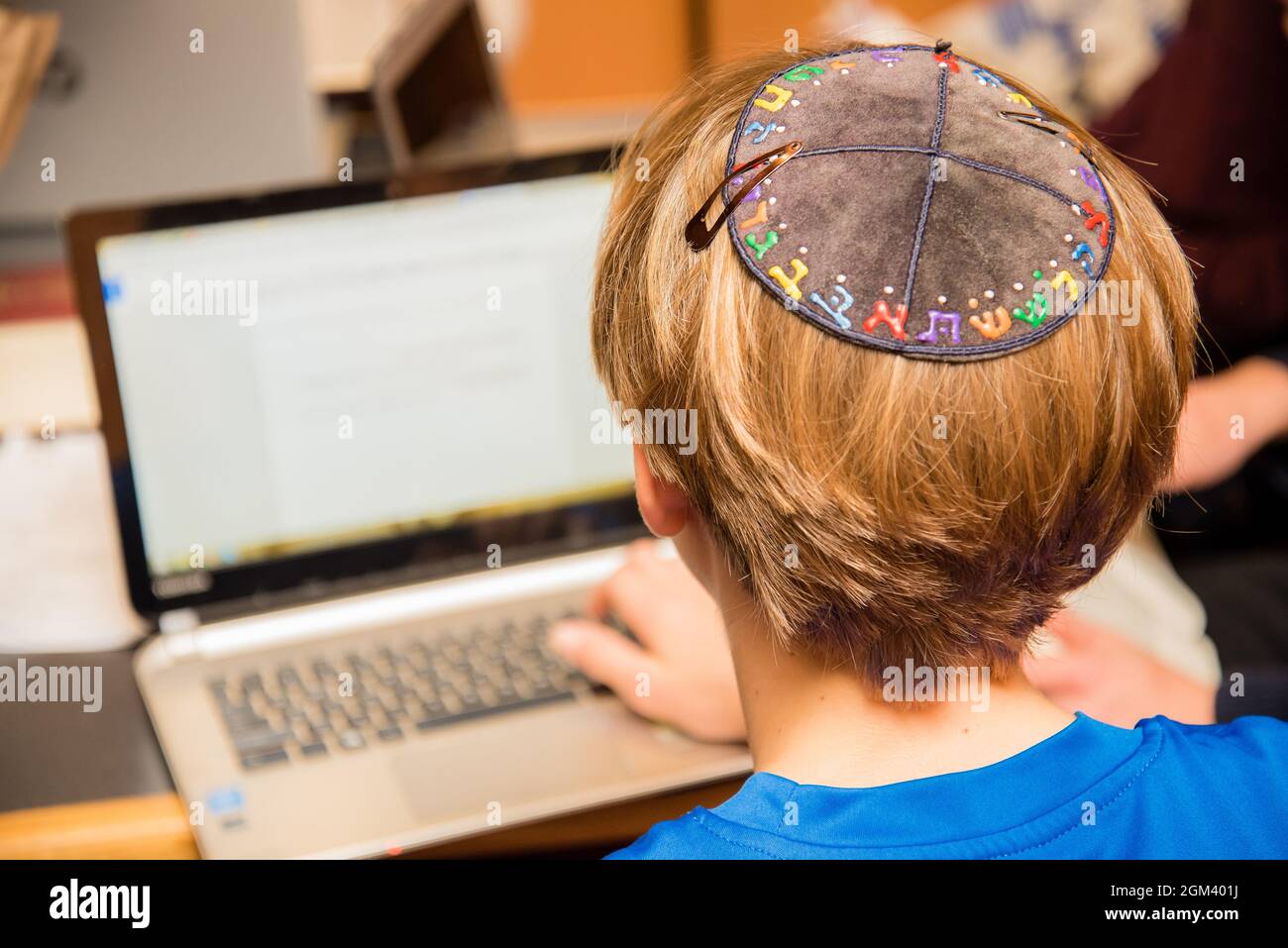 Jewish boy wearing yarmulke from the back sitting in a classroom ...