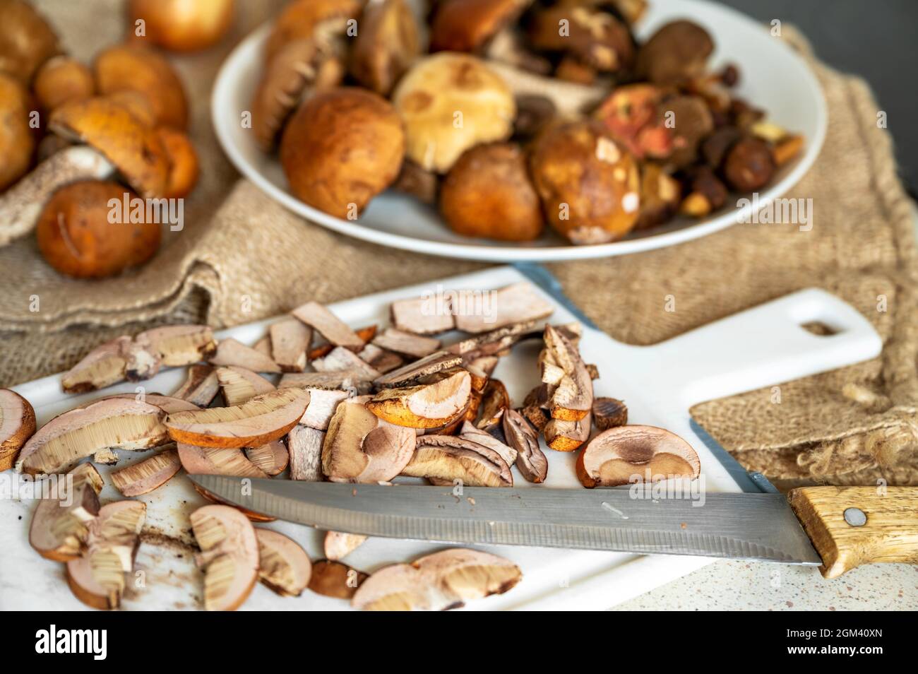 Heap of orange head forest mushroom (fungi Leccinum) on plate and sliced on kitchen board. Stock Photo