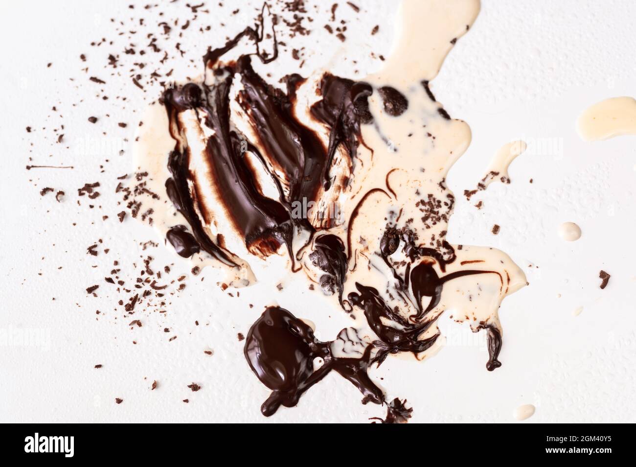 Dirty white background with melted chocolate and spilled cream, residue of chocolate preparation on kitchen table. Stock Photo