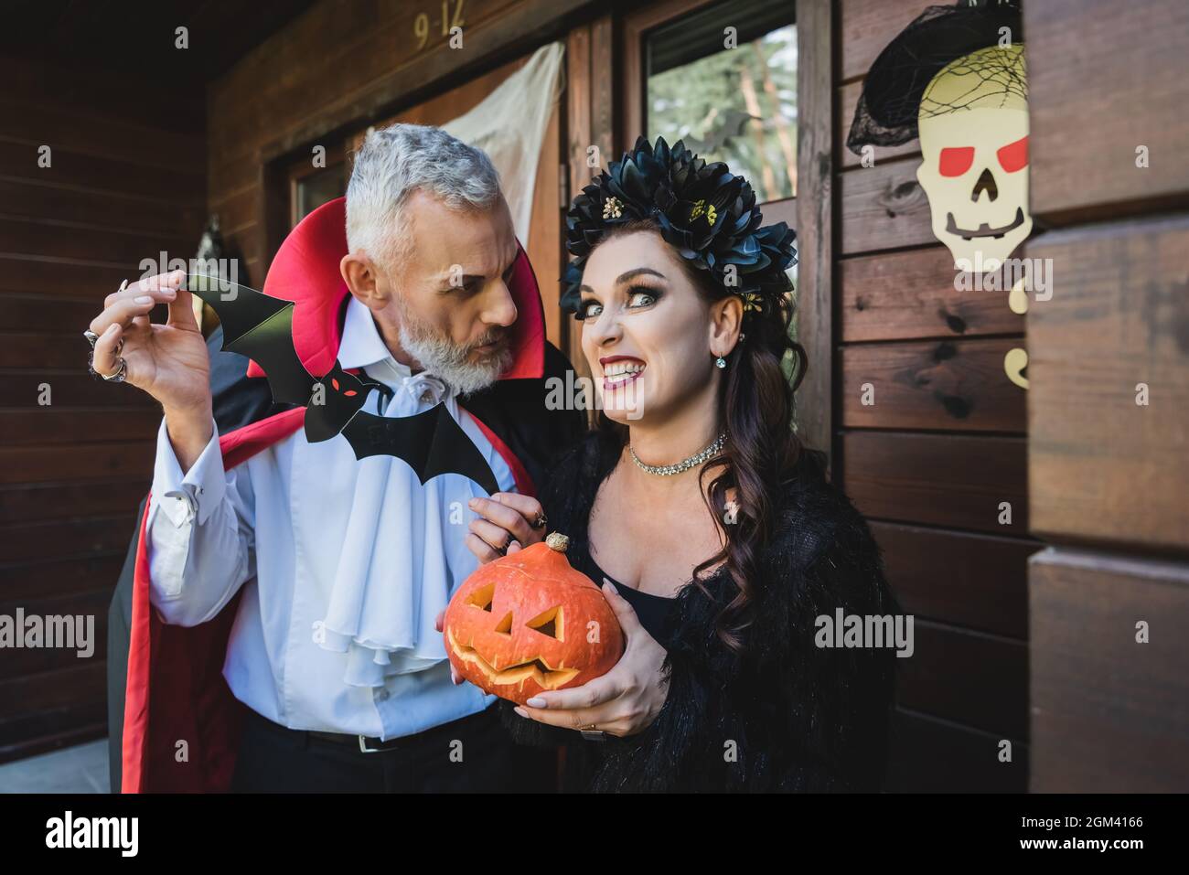 woman with halloween pumpkin grimacing near husband with paper cut bat Stock Photo