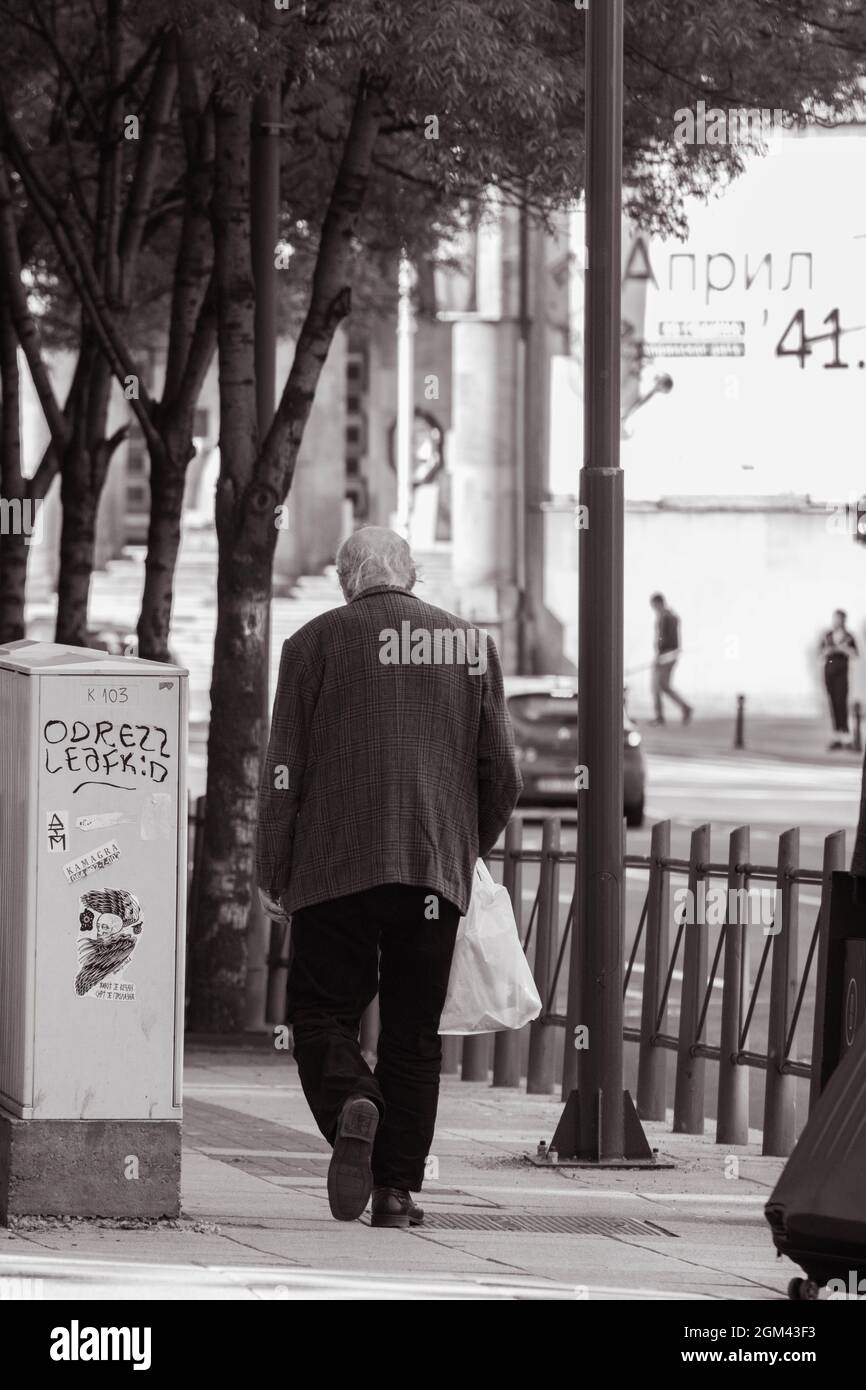 An old man walking down a city street in black and white Stock Photo ...