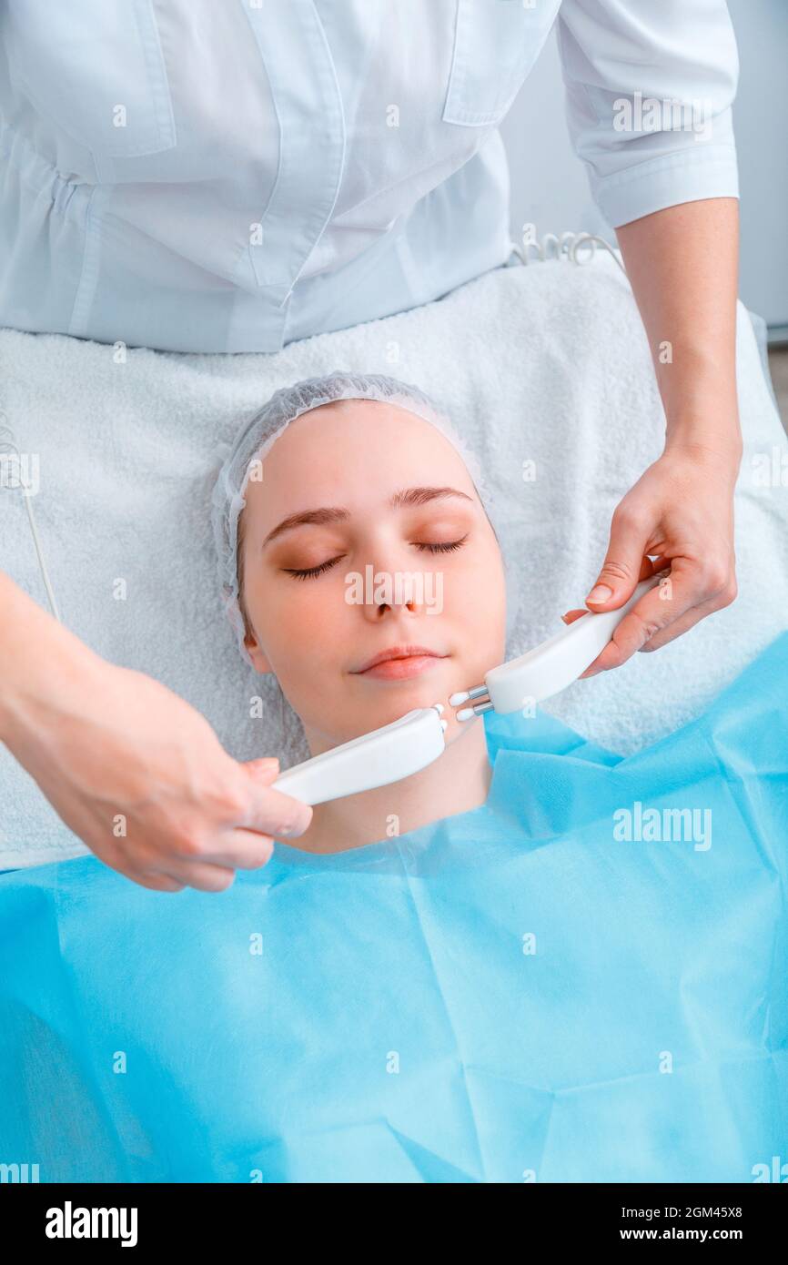 Microcurrents Cosmetology procedure. Beauty Doctor cosmetologist doing aesthetics facial therapy microcurrents. Cosmetology services to woman Stock Photo
