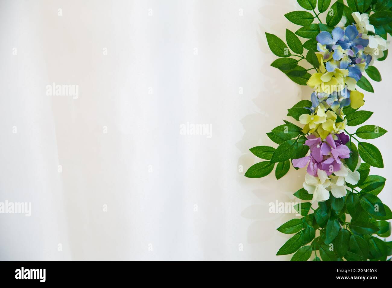 Green leaves and white, pink, yellow , blue, Artifical flower over white background. With area for copy space, text, words, graphic design. Macro deta Stock Photo