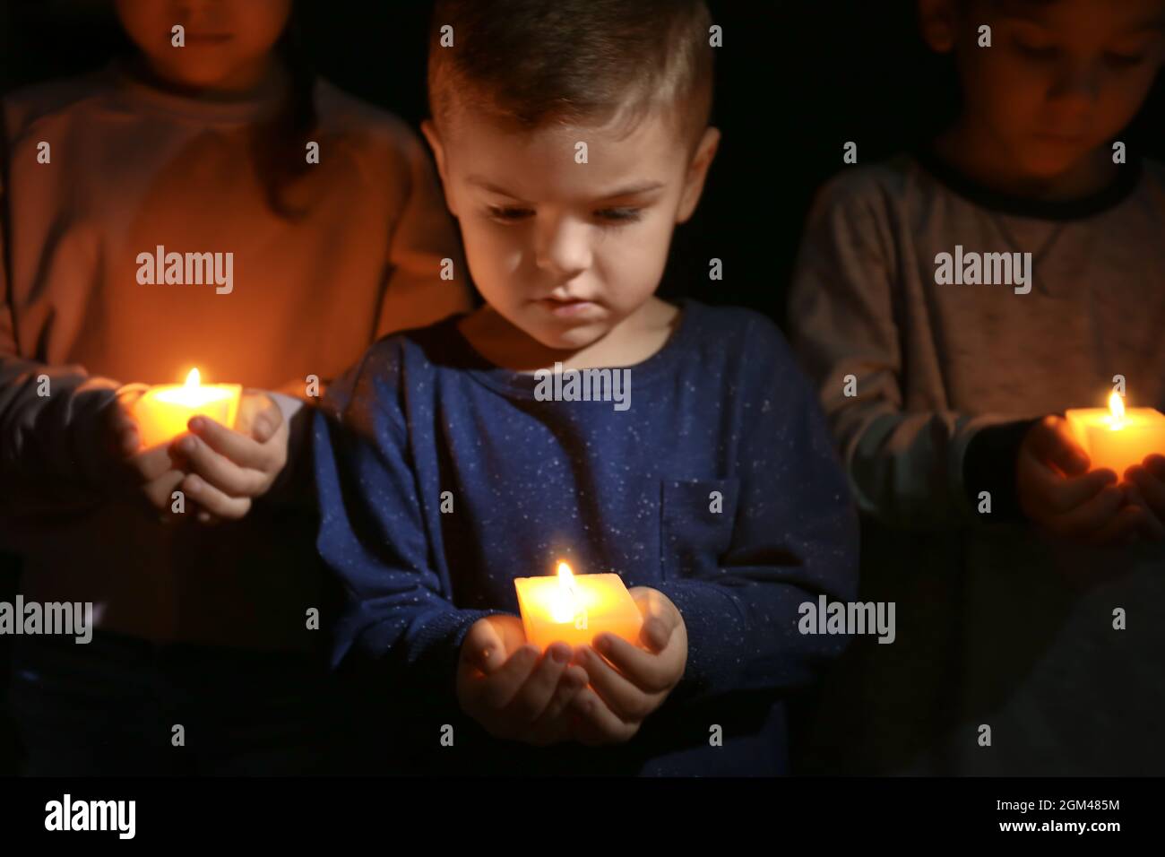 Little children holding burning candles in darkness Stock Photo Alamy