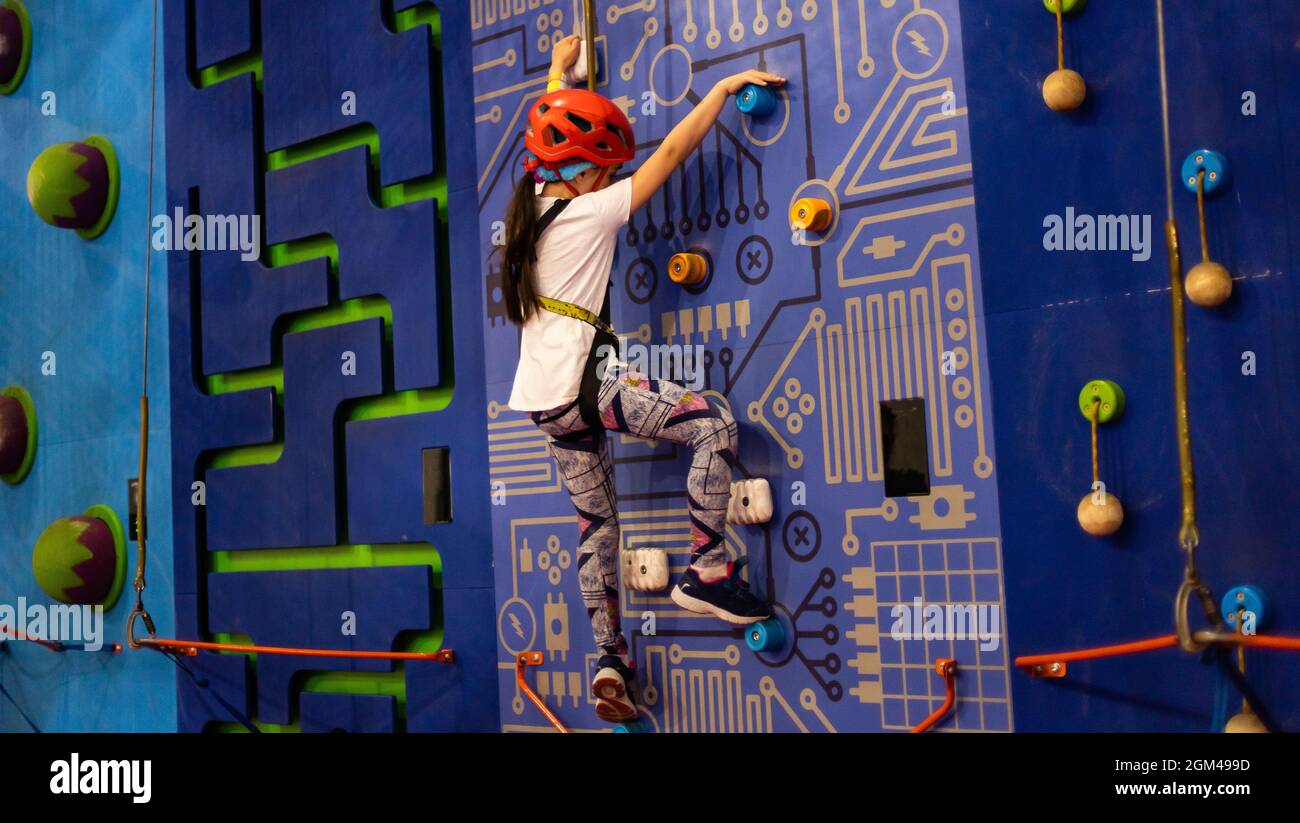 Little girl ascending in rock climbing gym Stock Photo Alamy