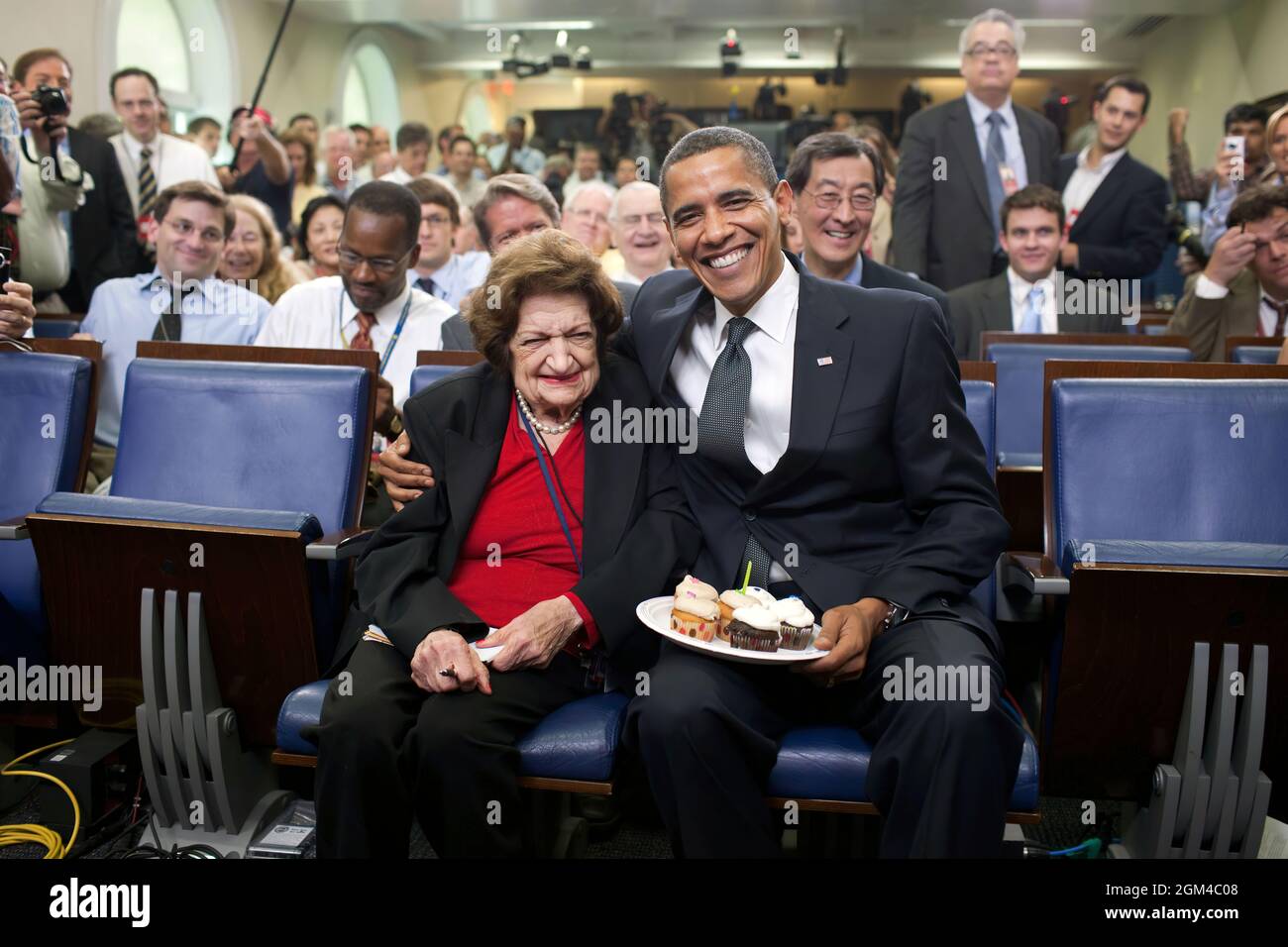 President Barack Obama presents cupcakes with a candle to Hearst White House columnist Helen Thomas in honor of her birthday in the James Brady Briefing Room, August 4, 2009. Thomas, who turned 89 , shares the same birthday as Obama, who turne 48 years old. (Official White House Photo by Pete Souza) This official White House photograph is being made available only for publication by news organizations and/or for personal use printing by the subject(s) of the photograph. The photograph may not be manipulated in any way and may not be used in commercial or political materials, advertisements, em Stock Photo