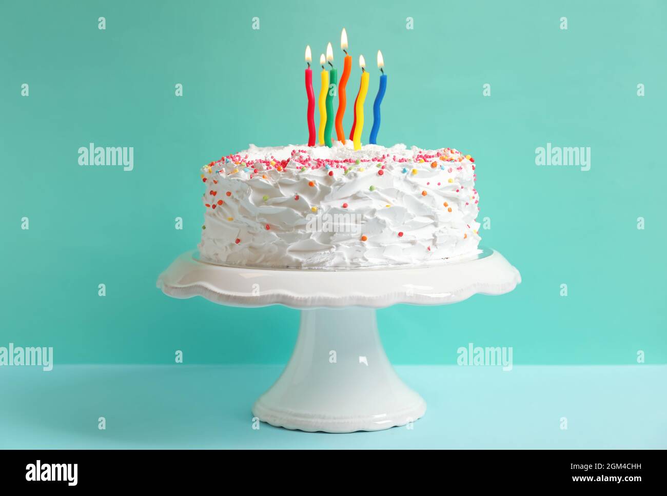 Stand with birthday cake and candles on table against color wall Stock ...