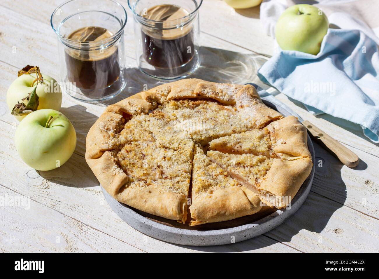 Apple galette with hazelnut streusel, served with coffee on a wooden background. Rustic style. Stock Photo