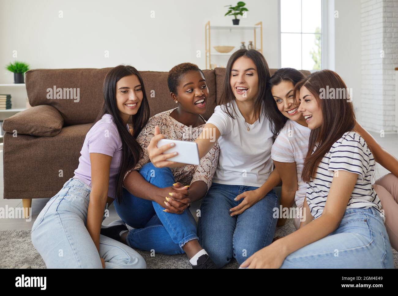 Group of happy diverse young women making funny faces and taking selfie ...