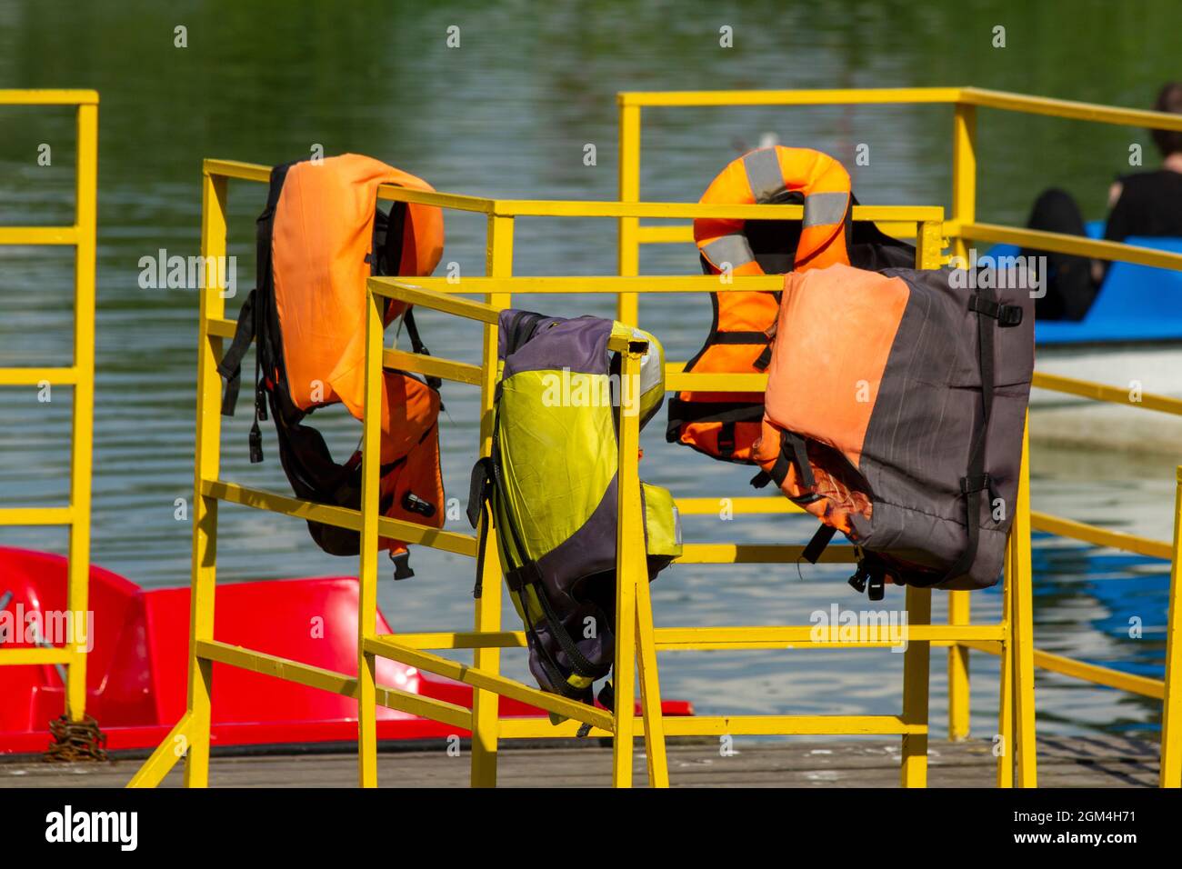 Life jackets hang on the yellow fence of the catamaran pier. Stock Photo