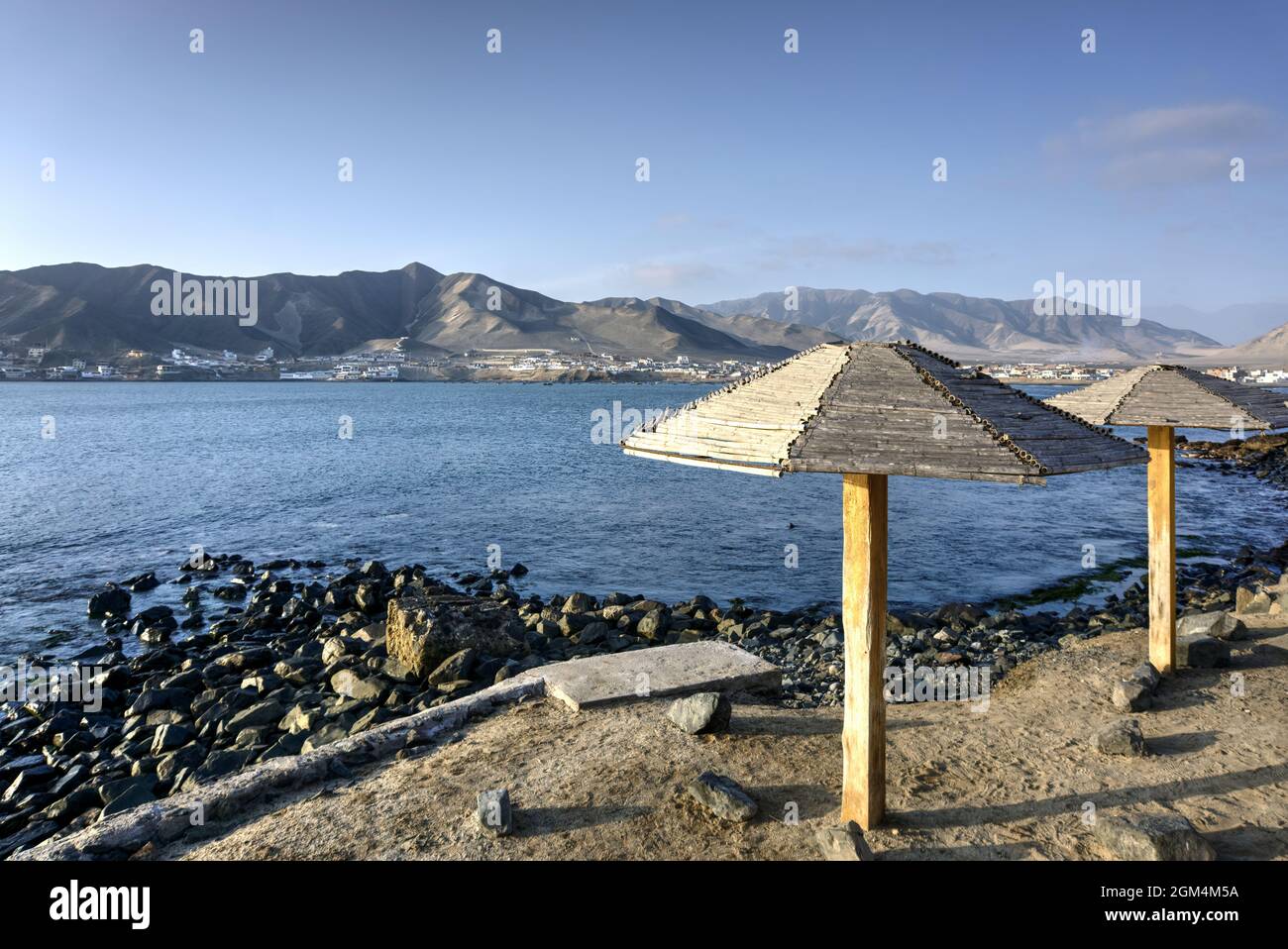 Tortugas, Casma, Peru - August 03, 2021: View of Tortugas across bay with mountains in background and umbrellas in foreground Stock Photo