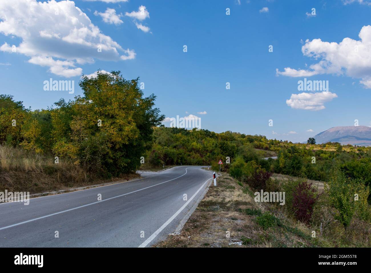 An asphalt empty road on a dry mountain ( Suva Planina ) in Serbia on an autumn day and white clouds in the sky. Beautiful natural background concept Stock Photo