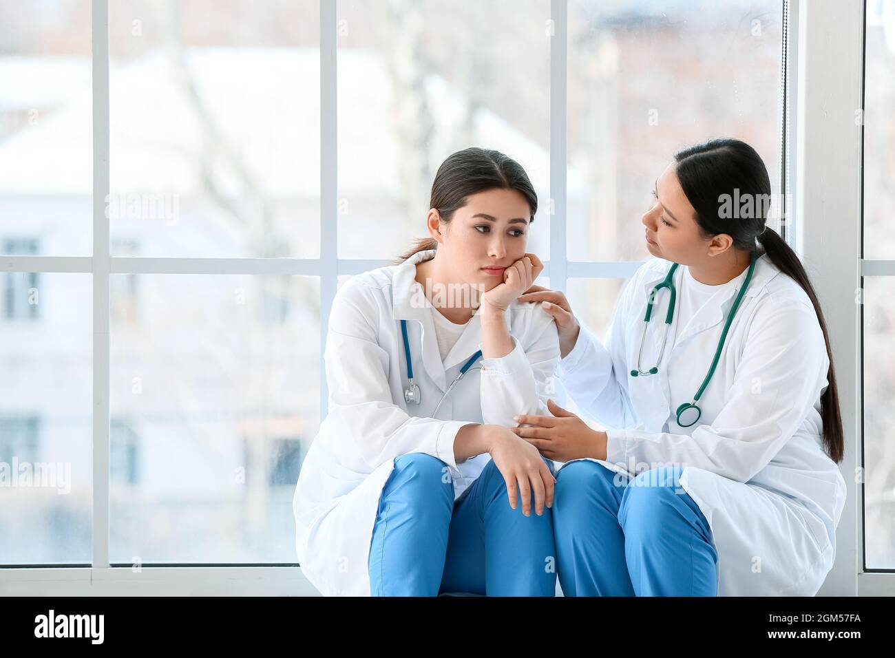 Female Asian doctor calming her colleague in hall of clinic Stock Photo ...