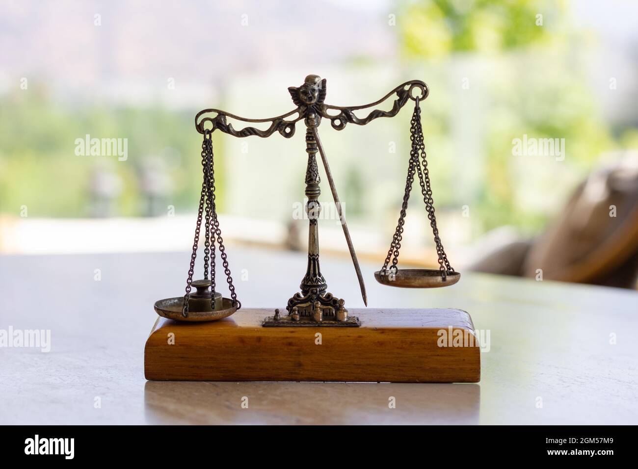 Imbalanced weighing scale miniature with weight on left plate. Weigh instrument, law, justice concepts Stock Photo