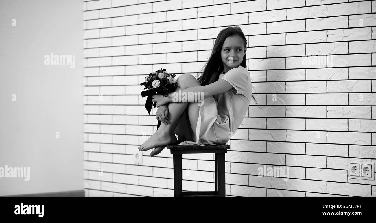 little girl is sitting on a chair and posing on the camera Stock Photo ...