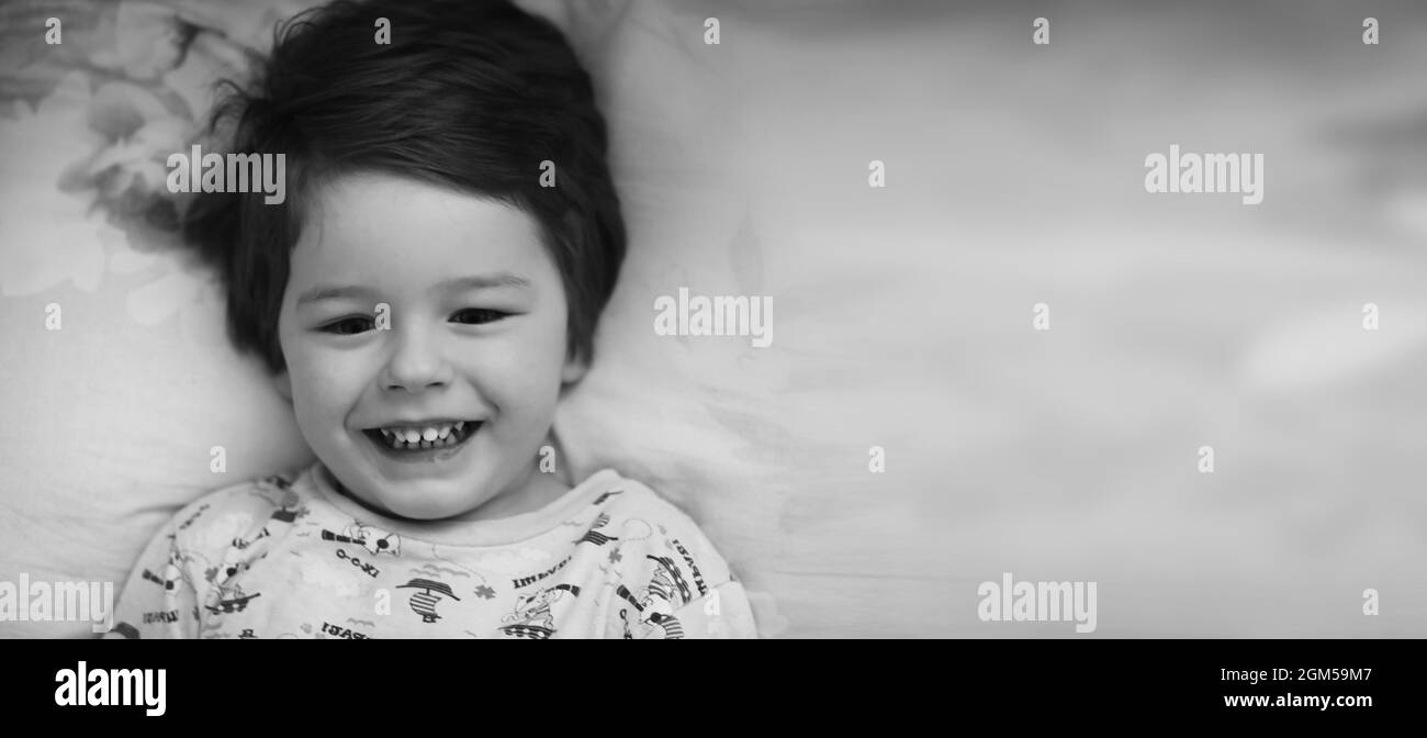 Black and white photo portrait of a young child lying on pillow Stock Photo