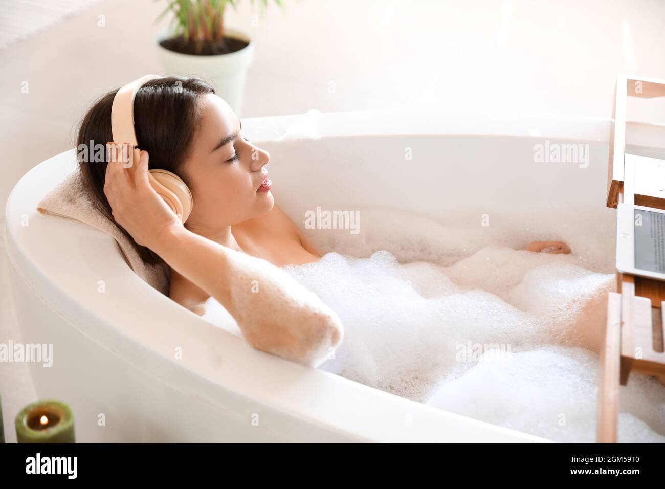 Young woman listening to music while taking bath at home Stock Photo