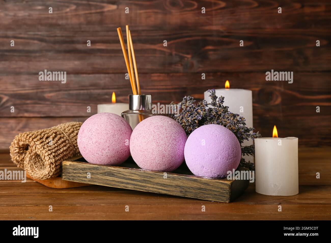 Beautiful spa composition with bath bombs, burning candles and lavender flowers on wooden background Stock Photo