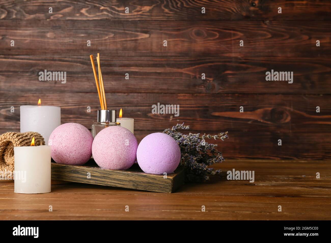 Beautiful spa composition with bath bombs, burning candles and lavender flowers on wooden background Stock Photo