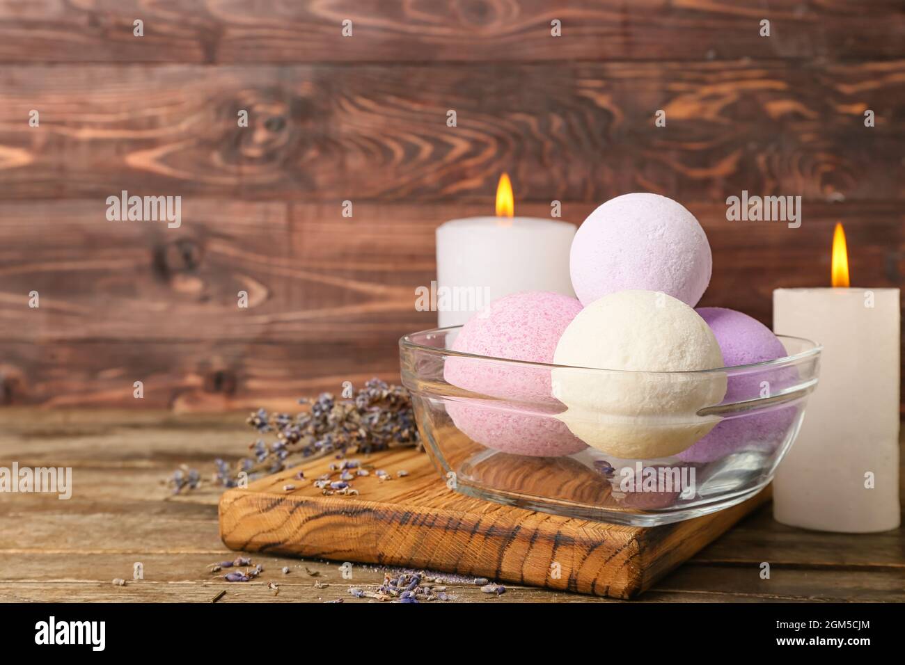 Bowl with lavender bath bombs and burning candles on wooden background Stock Photo