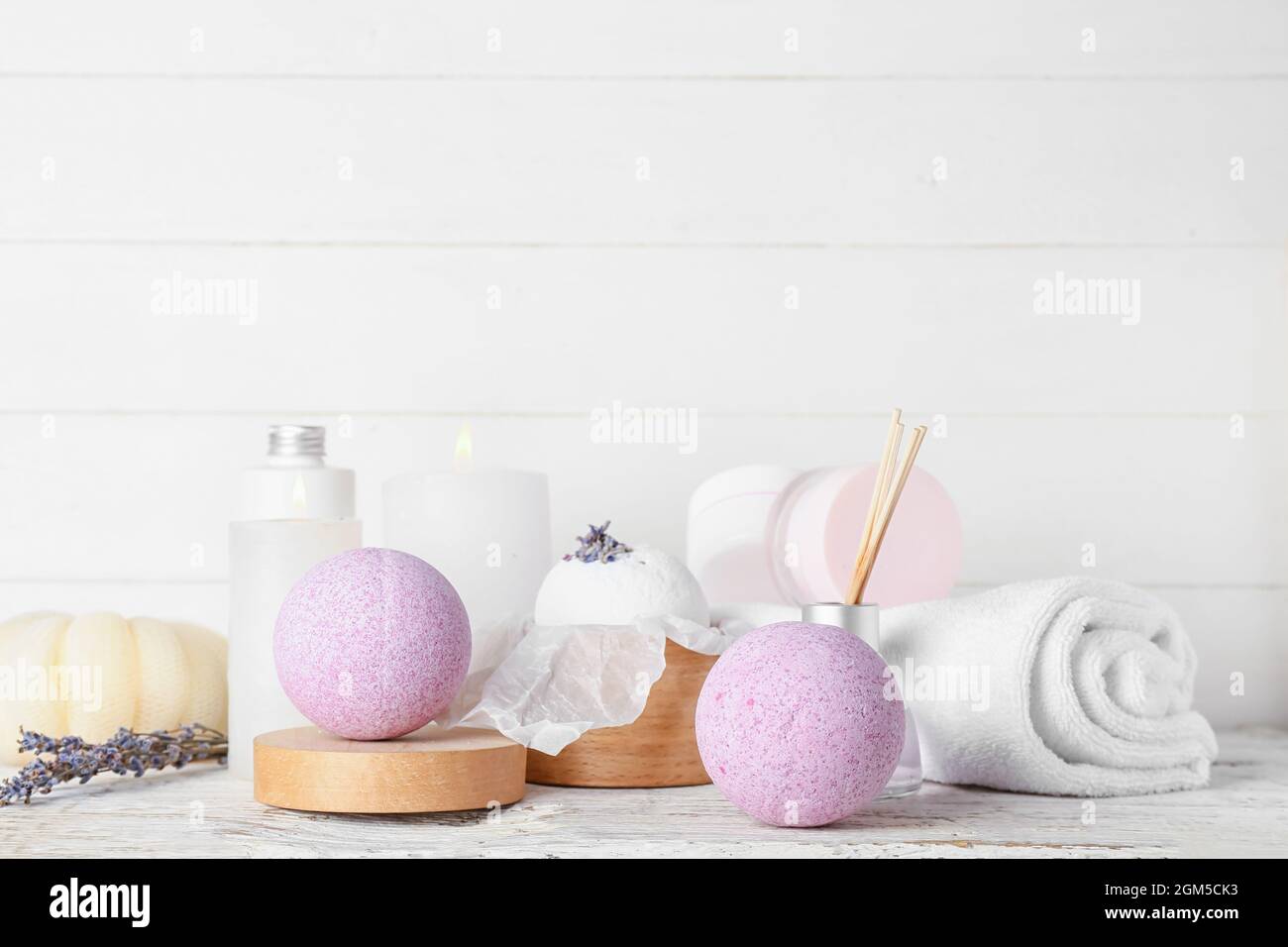 Beautiful spa composition with lavender bath bombs and burning candles on light wooden background Stock Photo