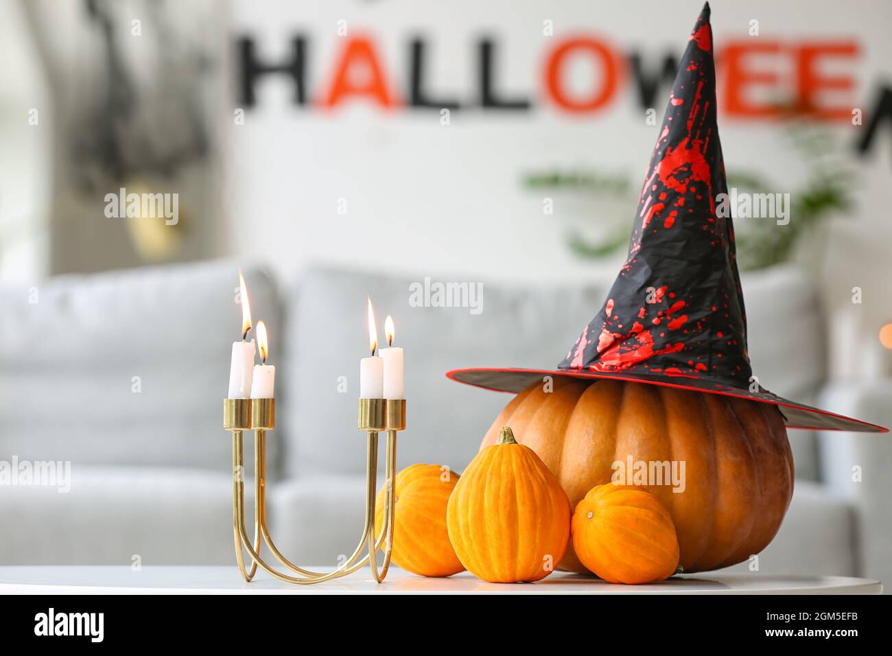 Halloween pumpkins with witch hat and candles on table in room Stock ...