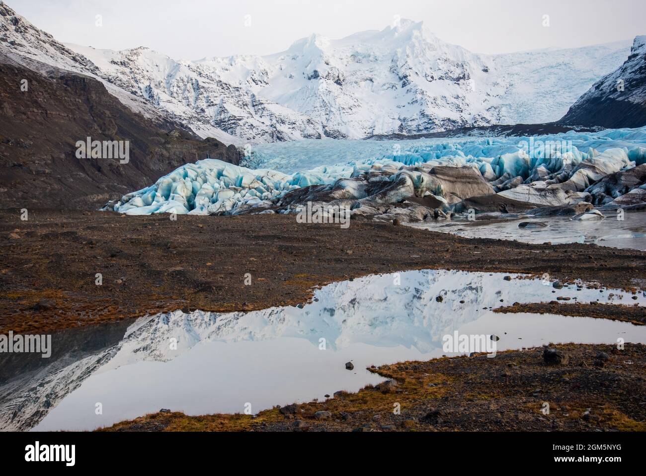 Bright blue Icelandic glacier with layers of glacier, volcanic ash, snow, and melted water. Stock Photo