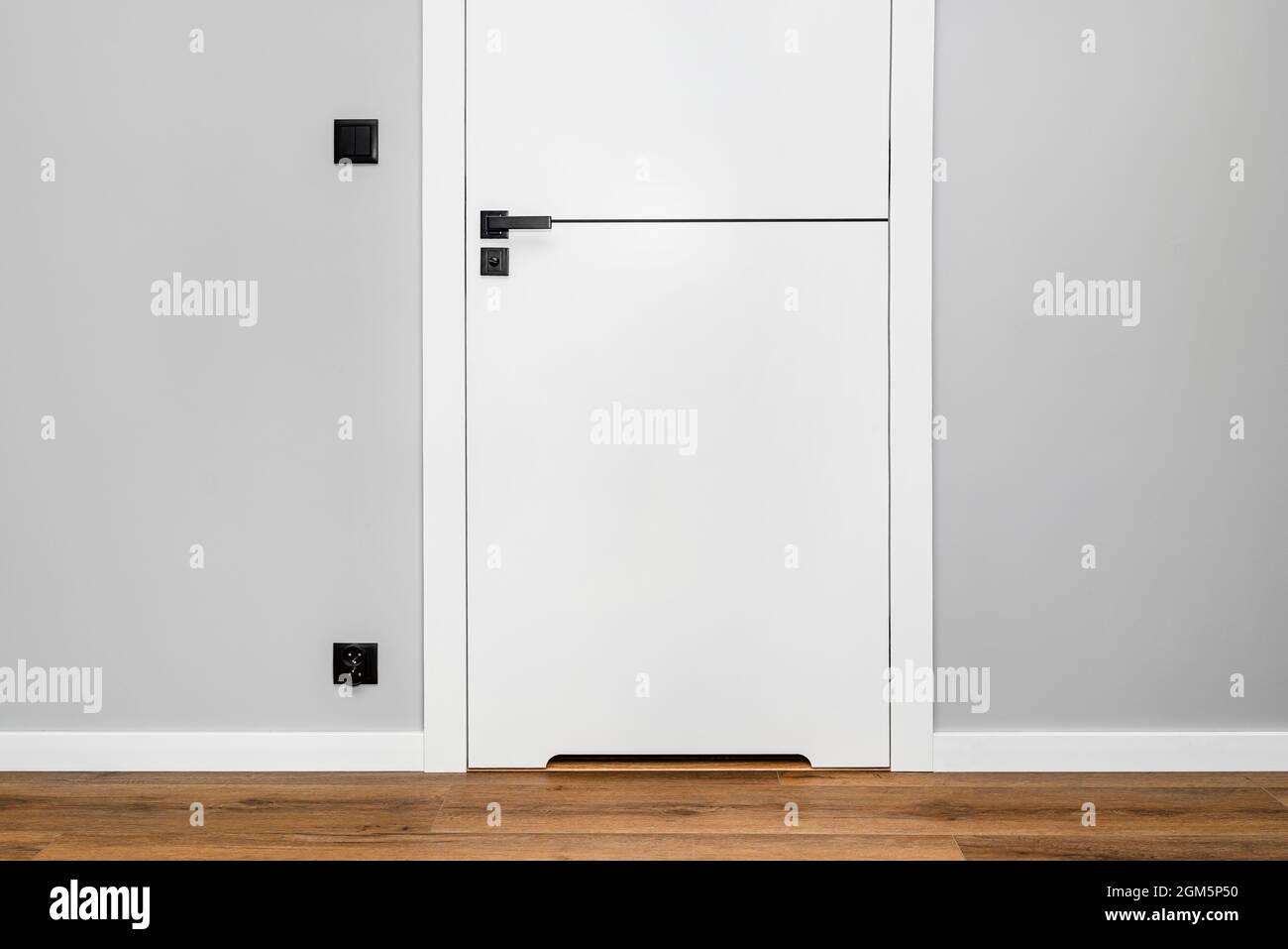 A white door with a ventilation undercut with a matte black handle and a black line in the