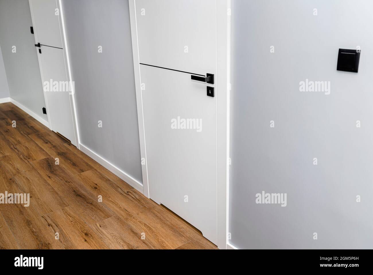 A white door with a ventilation undercut with a matte black handle and a black line in the
