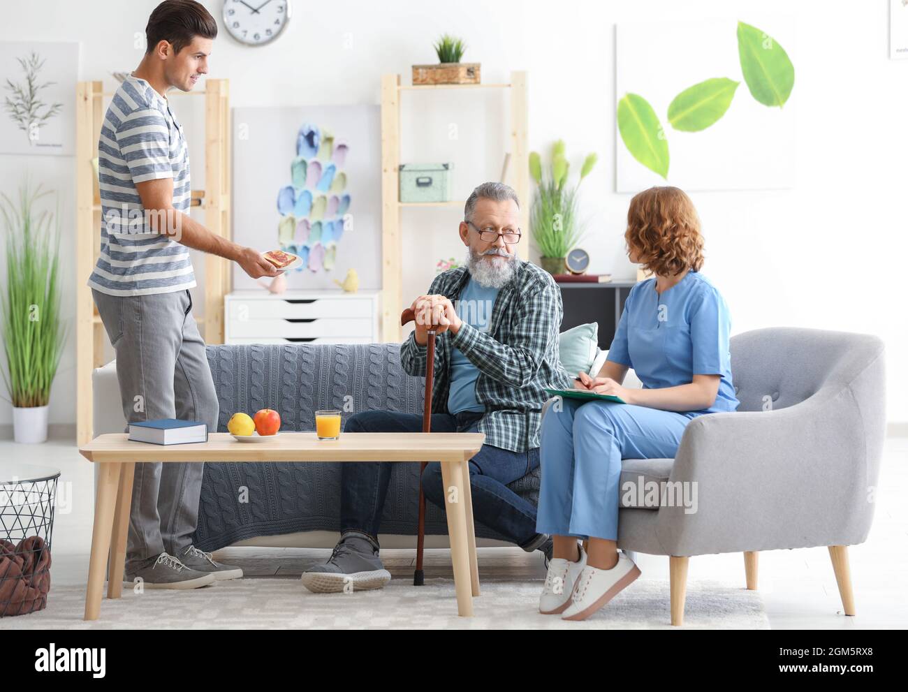 Caregiver with senior man and his son at home Stock Photo Alamy