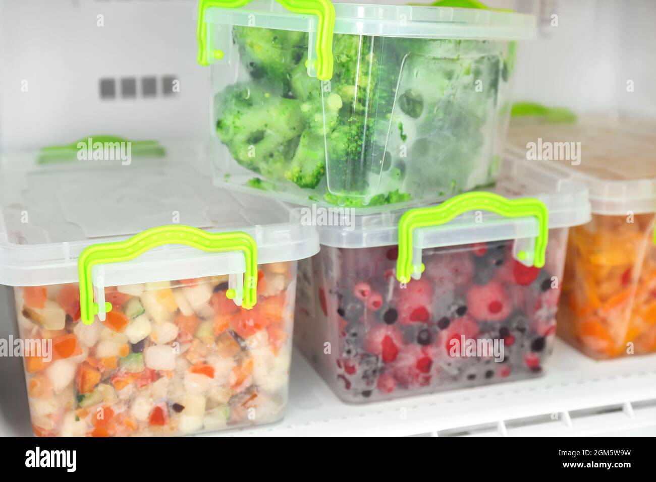 Containers with frozen berries and vegetables in freezer, closeup Stock
