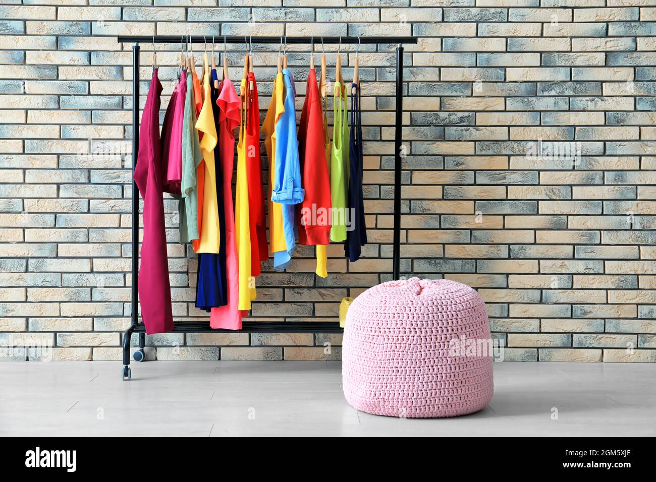 Rack with rainbow clothes near brick wall Stock Photo - Alamy