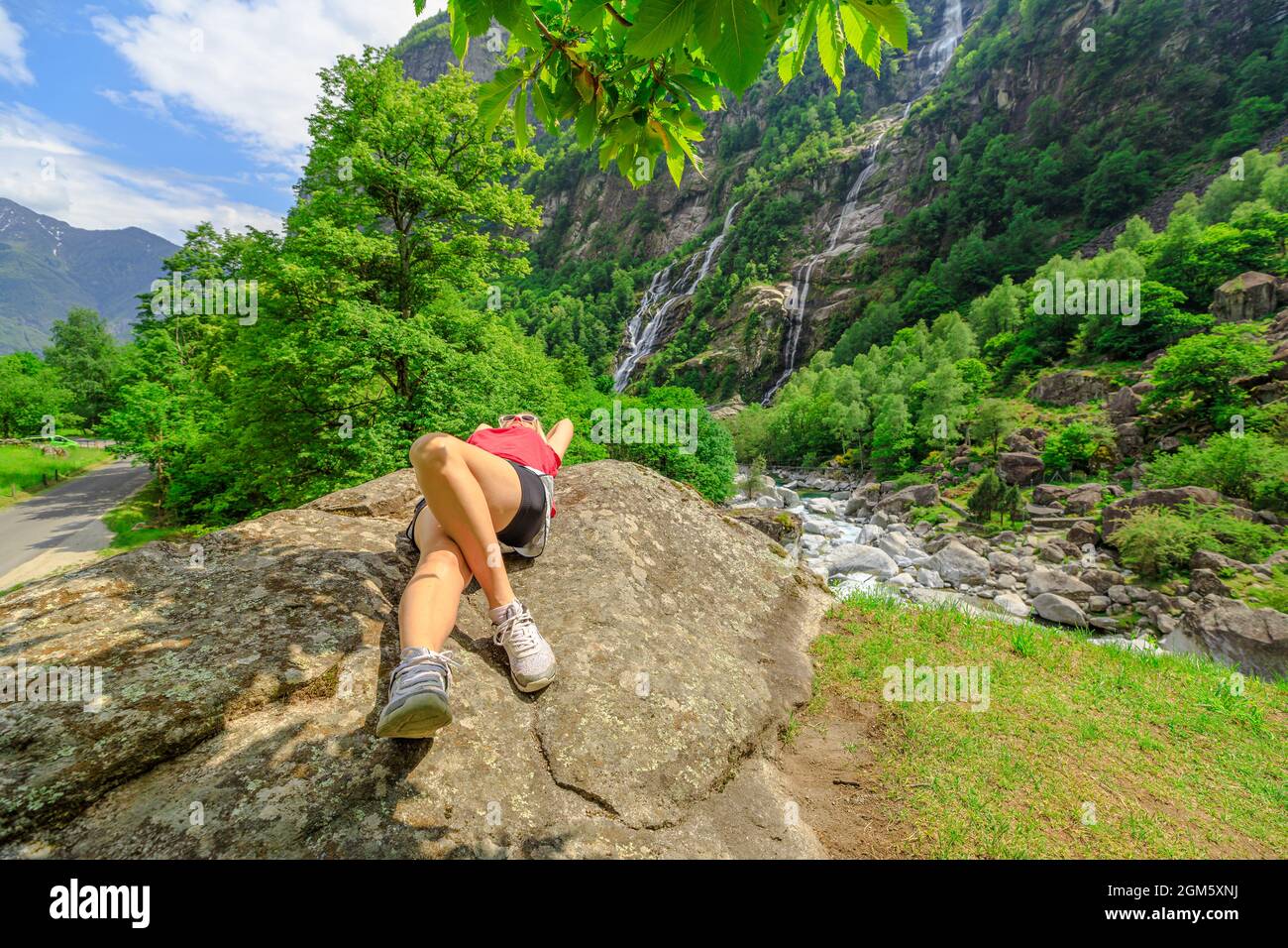 Peaceful woman resting at the old Roman stone bridge Steinbrucke over the Bavona River. The waterfall of Bavona valley in Switzerland by Bignasco town Stock Photo