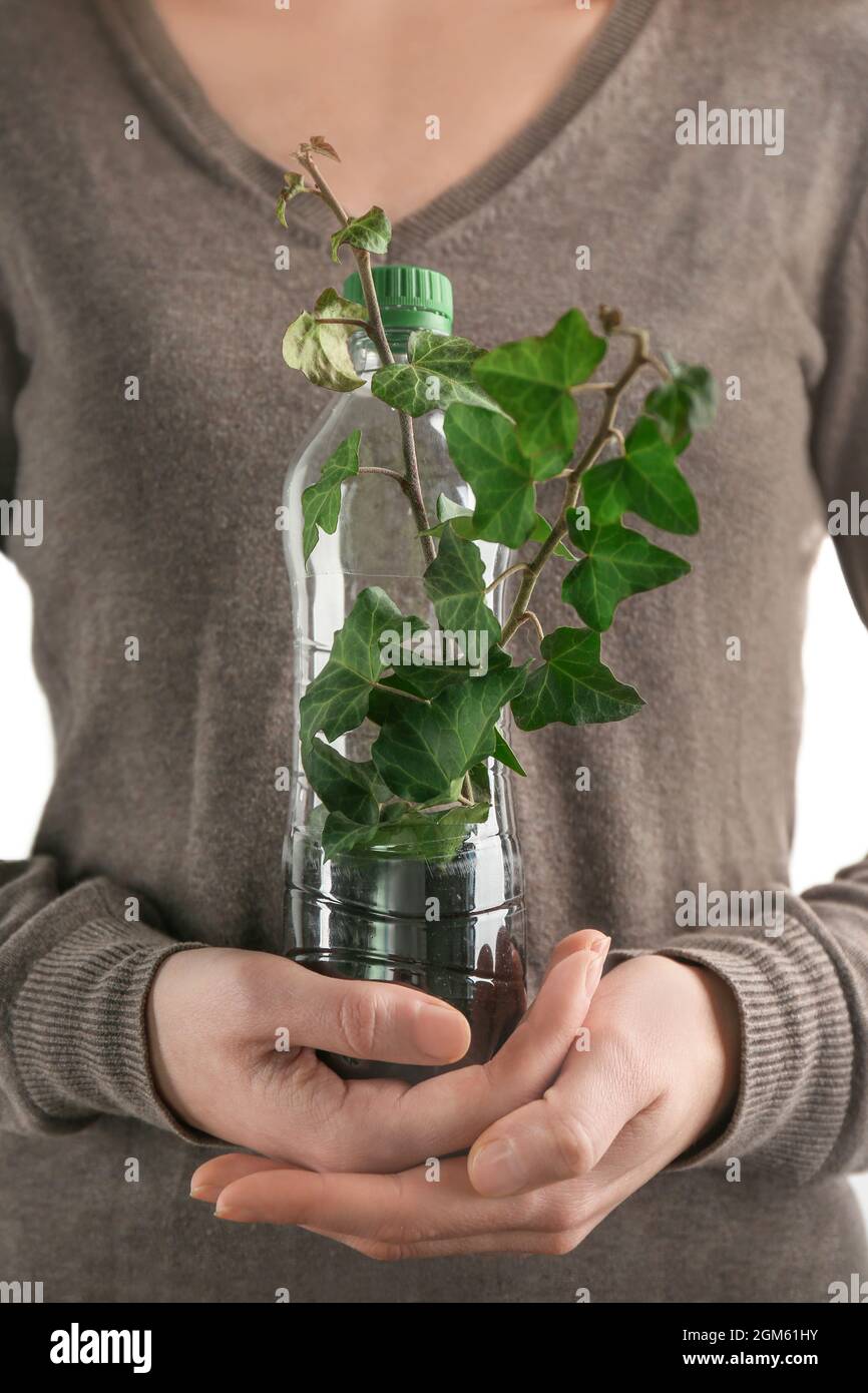 Young woman with plastic bottle used as container for growing plant
