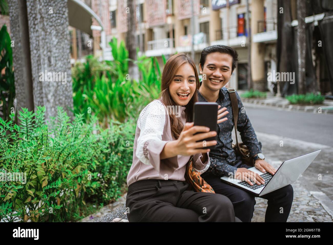 Happy woman using a smart phone taking selfie and video call with her partner Stock Photo