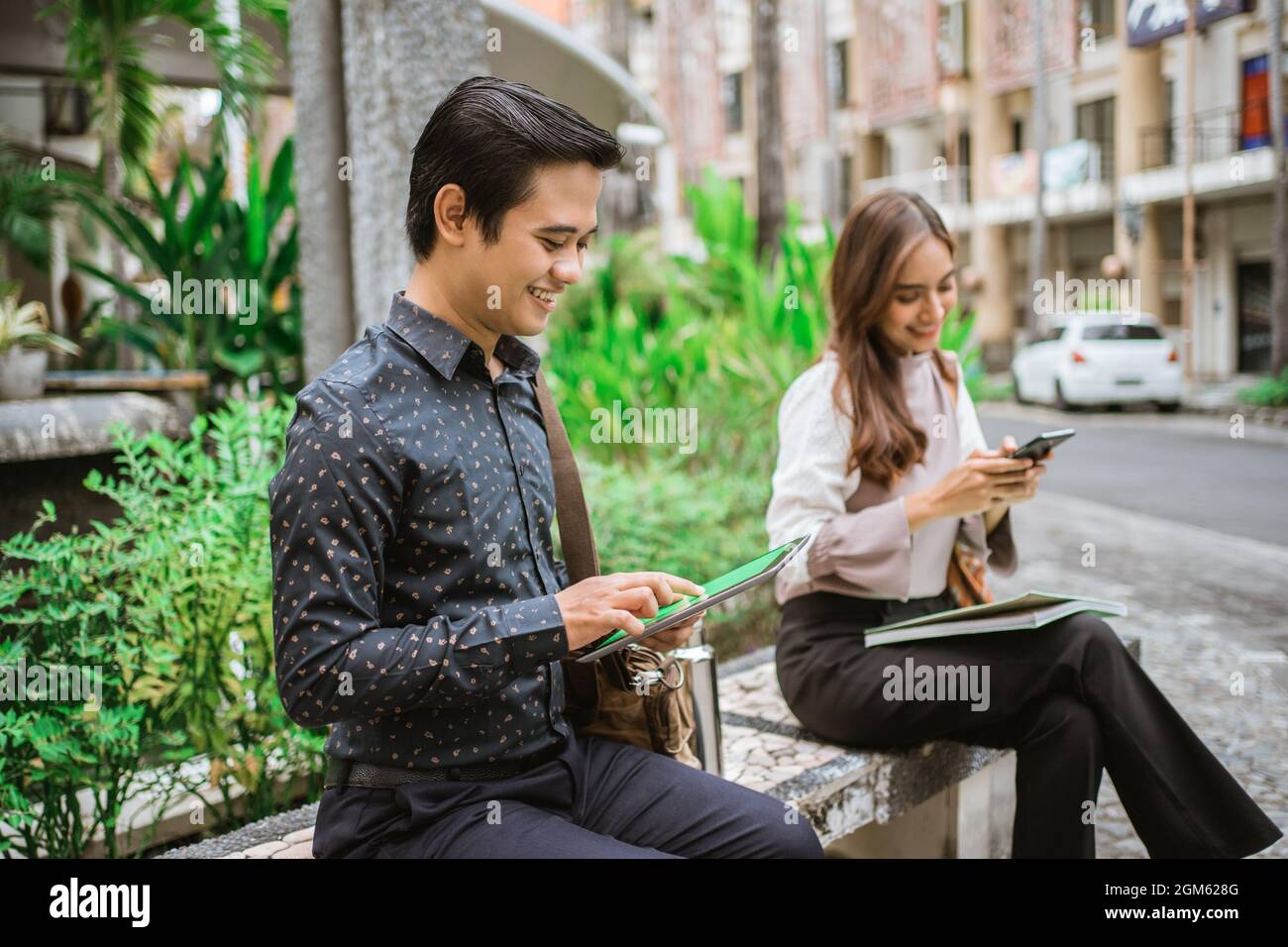 two busy worker sitting in the park during office break using phone Stock Photo