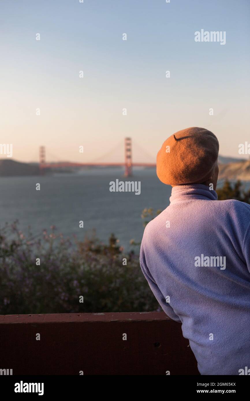 A woman leans on a railing enjoying a view of the Golden Gate Bridge. Stock Photo