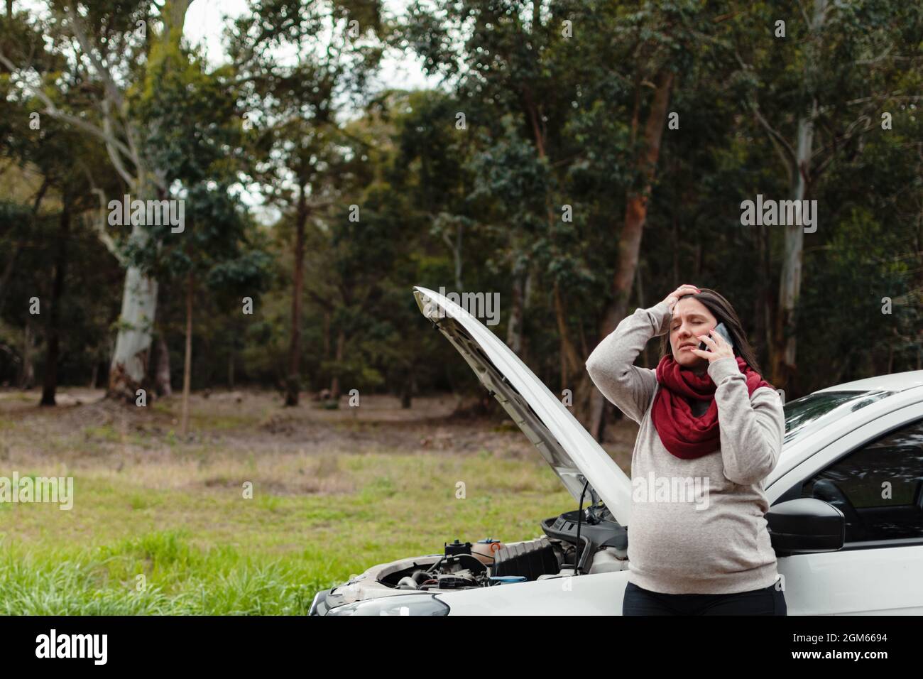 pregnant latina woman talking on the phone stressed with her broken car  behind her Stock Photo - Alamy