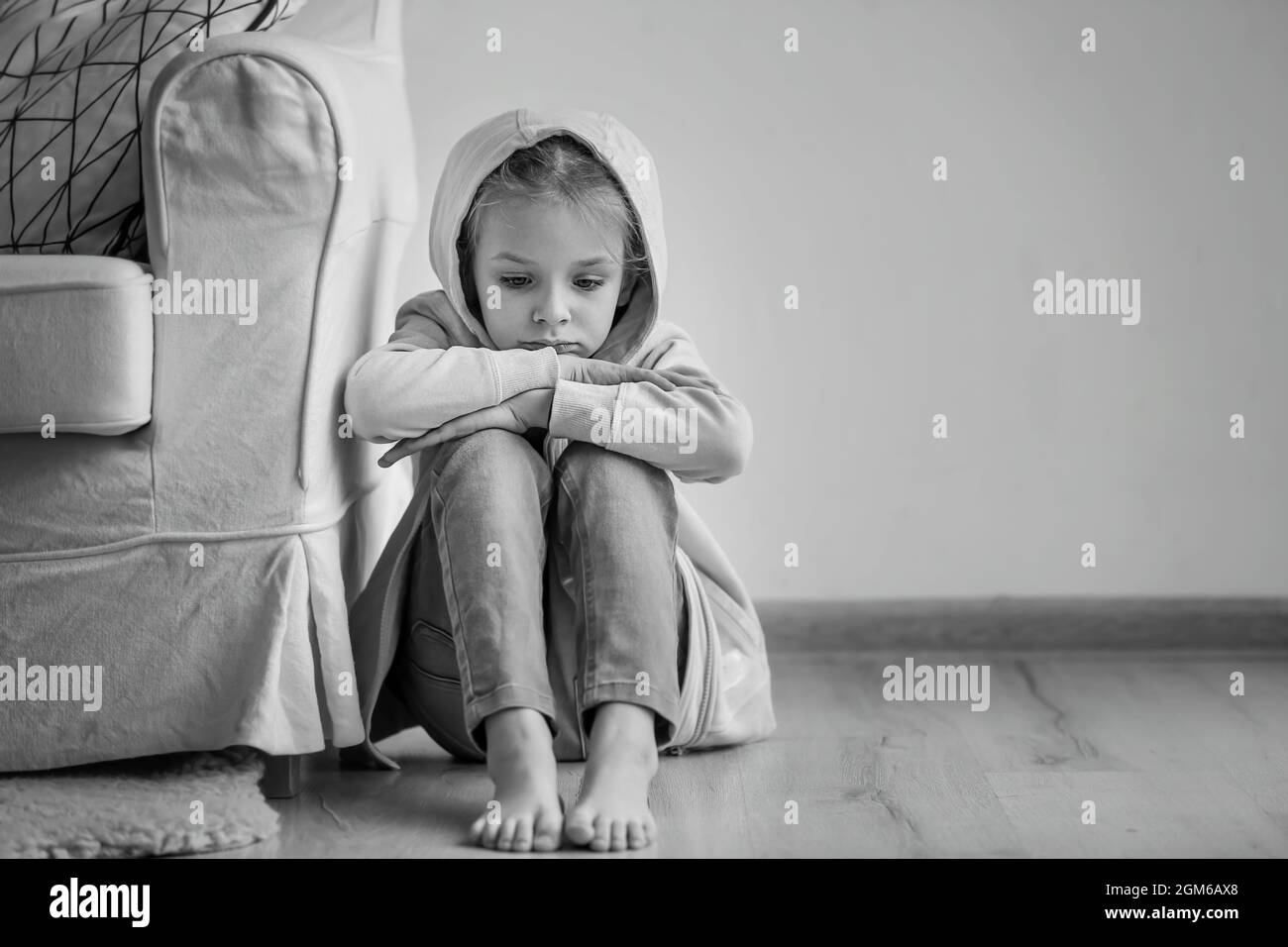 Sad little girl sitting on floor indoors, black and white effect Stock ...